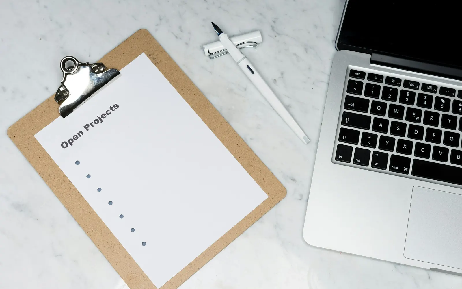 Illustrative photo: a clipboard with a checklist beside a laptop on marble. Not a sample of the SOP & Process Documentation Pack deliverable.